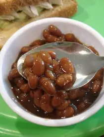 Spoonful of baked beans in a small white bowl.