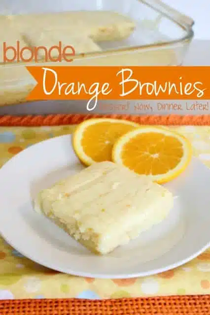 Orange brownie on a plate with orange cream cheese frosting.