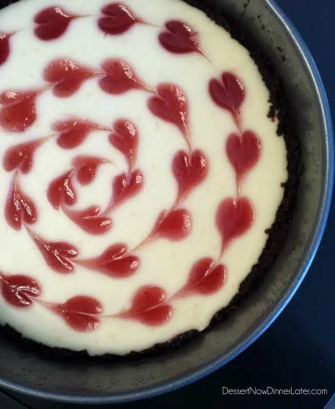 Cheesecake in springform pan with strawberry hearts.