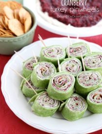 Cranberry Turkey Pinwheels have layers of cream cheese, spicy-sweet cranberry salsa, and thinly sliced turkey all rolled up in a spinach tortilla for a delicious party appetizer! From DessertNowDinnerLater.com