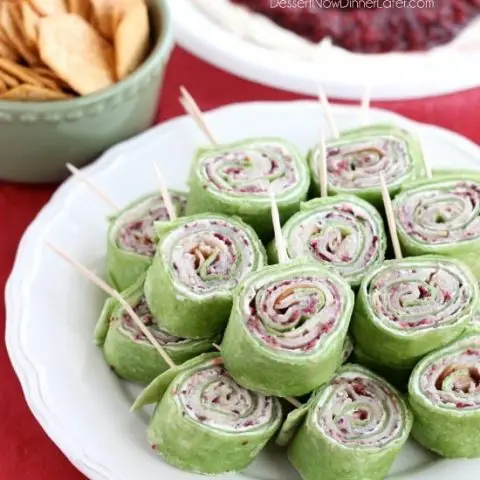 Cranberry Turkey Pinwheels have layers of cream cheese, spicy-sweet cranberry salsa, and thinly sliced turkey all rolled up in a spinach tortilla for a delicious party appetizer! From DessertNowDinnerLater.com