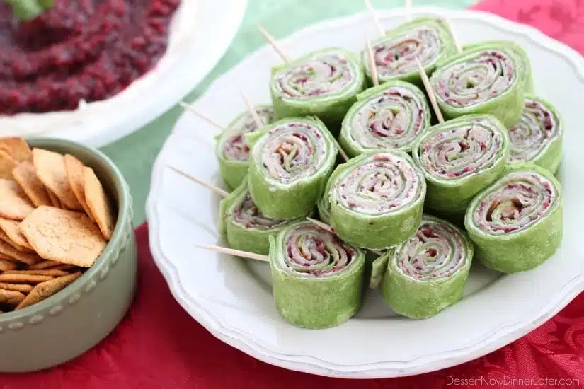 Cranberry Turkey Pinwheels have layers of cream cheese, spicy-sweet cranberry salsa, and thinly sliced turkey all rolled up in a spinach tortilla for a delicious party appetizer! From DessertNowDinnerLater.com