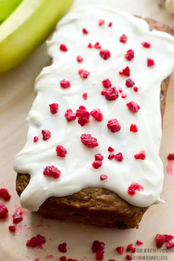 This super-soft and moist banana bread is exploding with a double-delight of juicy berries and perfectly covered in a tangy cream cheese icing. | dessertnowdinnerlater.com