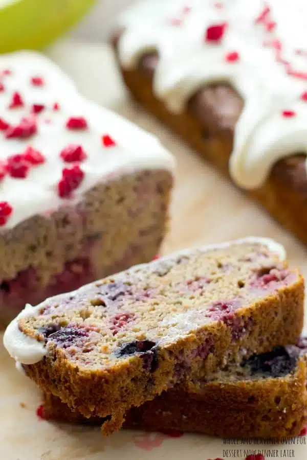 This super-soft and moist banana bread is exploding with a double-delight of juicy berries and perfectly covered in a tangy cream cheese icing. | dessertnowdinnerlater.com