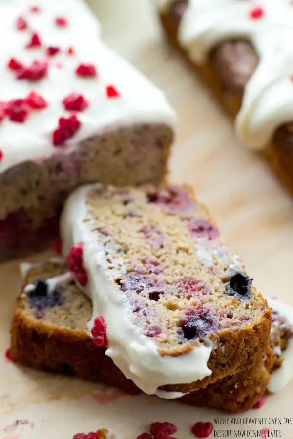 This super-soft and moist banana bread is exploding with a double-delight of juicy berries and perfectly covered in a tangy cream cheese icing. | dessertnowdinnerlater.com