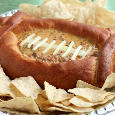 This Football Dip Bowl is made with a frozen whole wheat dough that is shaped into a football with a place to hold your favorite queso dip! Make laces with cut up string cheese and you have a football themed party food! (Step-by-step photos included.)
