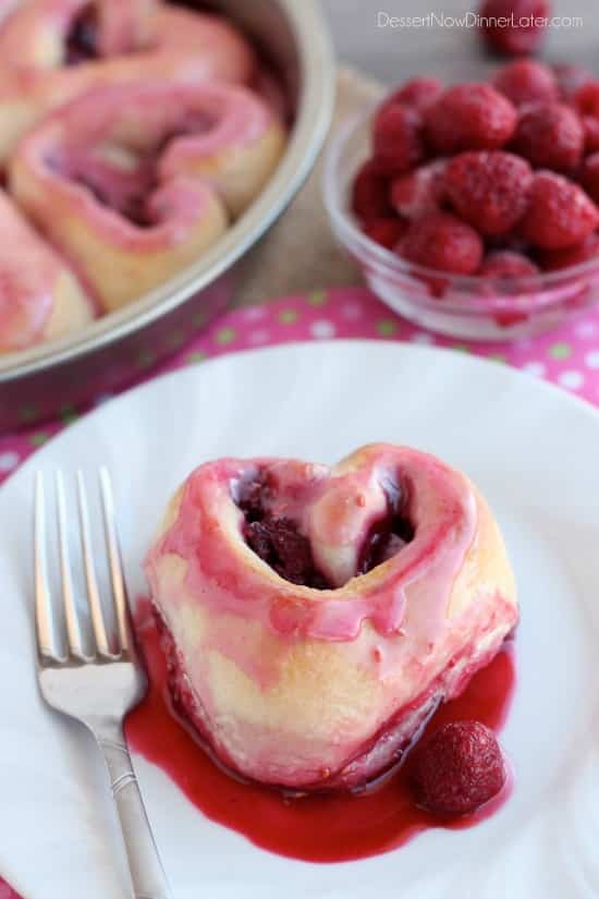 Heart shaped roll with a pink raspberry glaze on a plate.