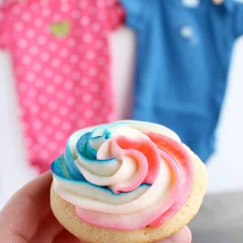 These Gender Reveal Cupcakes have pink, blue, and white swirled frosting on top that hides the secret colored heart in the center of the cupcake revealing the baby's gender when you bite into it! (Step-by-Step Photo Tutorial)