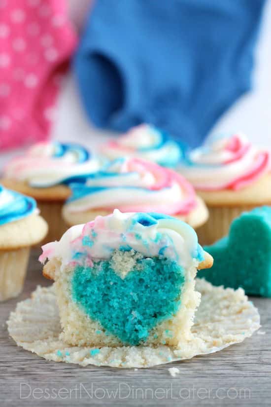 These Gender Reveal Cupcakes have pink, blue, and white swirled frosting on top that hides the secret colored heart in the center of the cupcake revealing the baby's gender when you bite into it! (Step-by-Step Photo Tutorial)