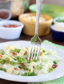 Sarah's Salad from Utah's Lion House restaurant uses crisp iceberg lettuce, peas, bacon, green onions, and swiss cheese tossed in a simple, sweet dressing.