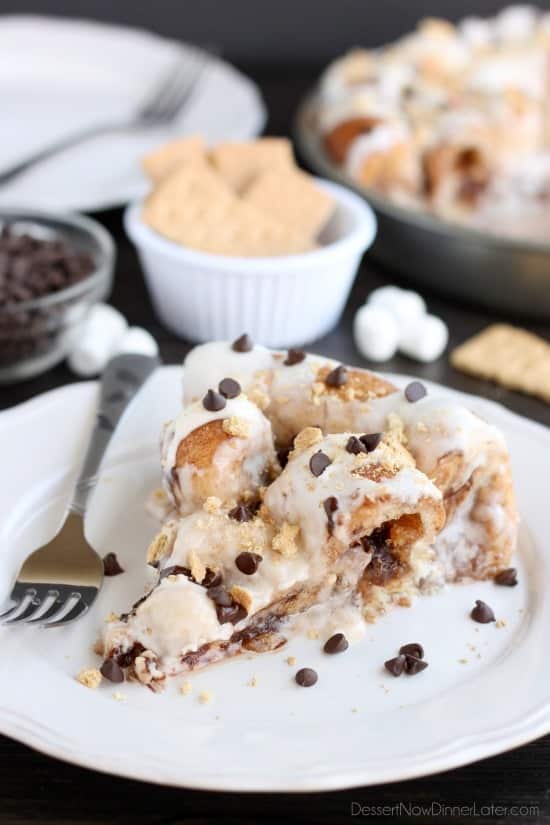 Crushed graham crackers, mini chocolate chips, and mini marshmallows are rolled up in buttery cinnamon sugar rolls to create this S'mores Cinnamon Roll Cake. Top it all off with a marshmallow frosting and extra toppings for a delicious dessert!