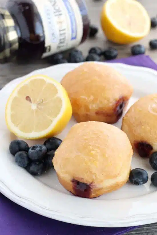 These Jelly Filled Mini Donuts make the perfect breakfast or dessert! Lemon glazed donuts are made easy with refrigerated biscuit dough, and are stuffed with a naturally sweetened blueberry lemon fruit spread.