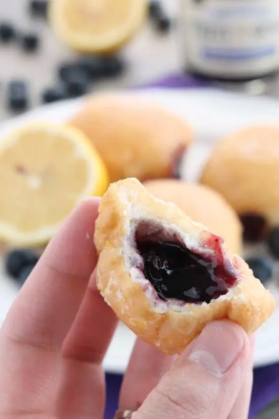 These Jelly Filled Mini Donuts make the perfect breakfast or dessert! Lemon glazed donuts are made easy with refrigerated biscuit dough, and are stuffed with a naturally sweetened blueberry lemon fruit spread.