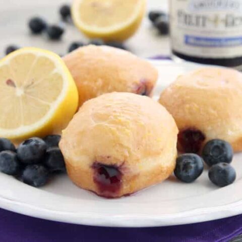 These Jelly Filled Mini Donuts make the perfect breakfast or dessert! Lemon glazed donuts are made easy with refrigerated biscuit dough, and are stuffed with a naturally sweetened blueberry lemon fruit spread.