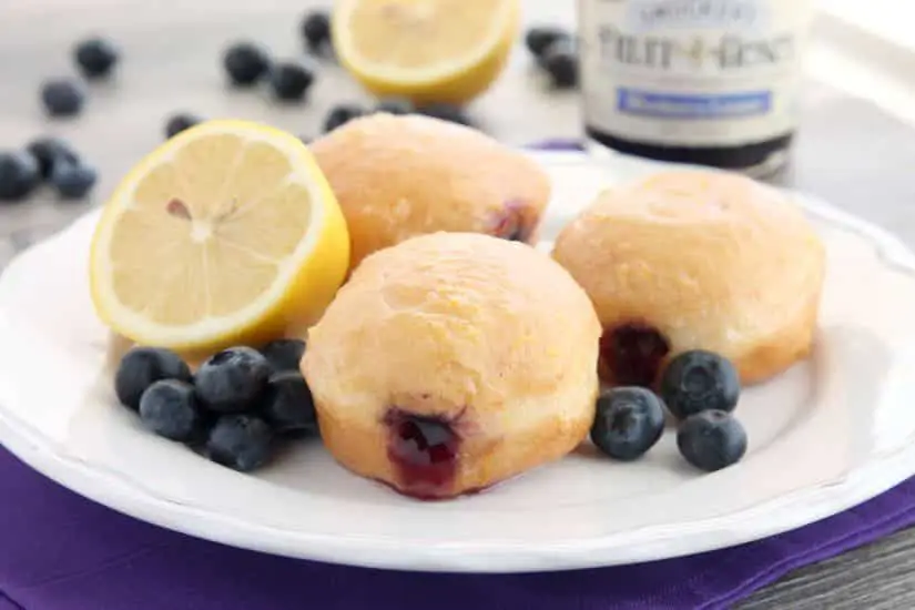 These Jelly Filled Mini Donuts make the perfect breakfast or dessert! Lemon glazed donuts are made easy with refrigerated biscuit dough, and are stuffed with a naturally sweetened blueberry lemon fruit spread.