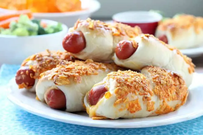 Frozen dough, nacho tortilla chips, and extra cheese transform ordinary pigs in a blanket into these extraordinary crunchy nacho dogs. 