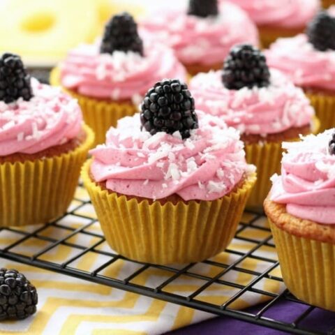 Blackberry Piña Colada Cupcakes - Moist coconut cupcakes with a sweet pineapple and rum filling topped with fresh blackberry frosting. A delicious drink inspired cupcake with a twist!