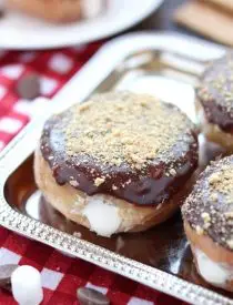 Glazed and ganached, with crushed graham crackers on top, and a marshmallow buttercream center, these S'mores Donuts are delicious and decadent.