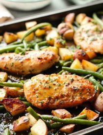 This one pan chicken dinner has the most delicious honey garlic glazed chicken alongside tenderly roasted potatoes and green beans. Plus, it's so easy and flavorful, you'll make again and again!