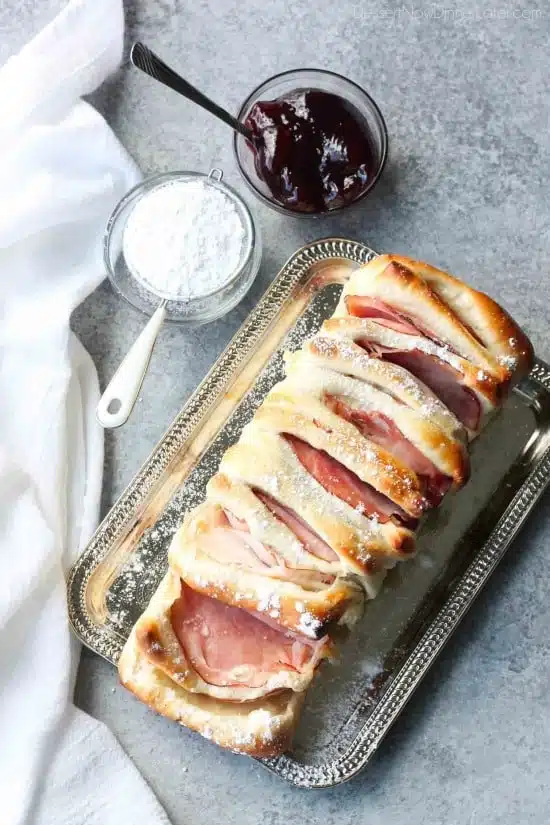 This Monte Cristo Pull Apart Bread is full of savory meats and melty cheese. It's topped with a dusting of powdered sugar and served with raspberry preserves. Works great as a breakfast, lunch, dinner, or appetizer!