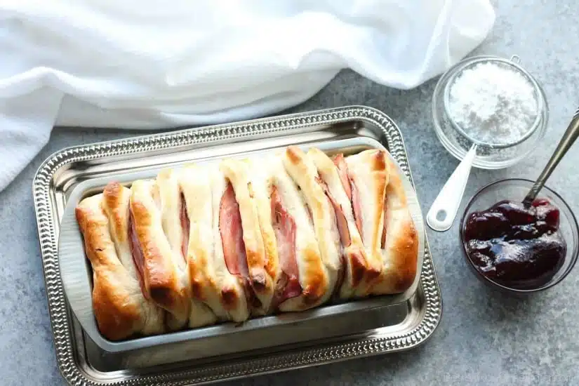 This Monte Cristo Pull Apart Bread is full of savory meats and melty cheese. It's topped with a dusting of powdered sugar and served with raspberry preserves. Works great as a breakfast, lunch, dinner, or appetizer!