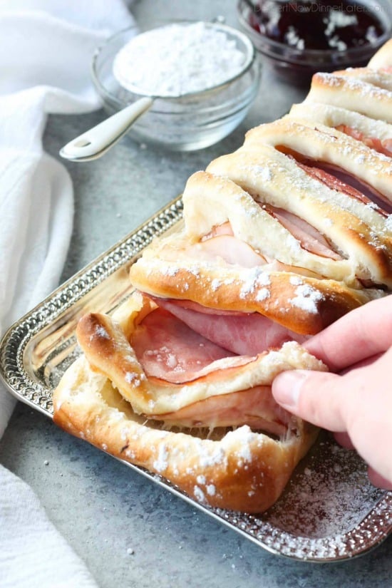 This Monte Cristo Pull Apart Bread is full of savory meats and melty cheese. It's topped with a dusting of powdered sugar and served with raspberry preserves. Works great as a breakfast, lunch, dinner, or appetizer!