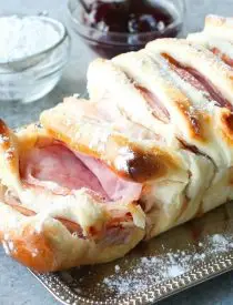 This Monte Cristo Pull Apart Bread is full of savory meats and melty cheese. It's topped with a dusting of powdered sugar and served with raspberry preserves. Works great as a breakfast, lunch, dinner, or appetizer!