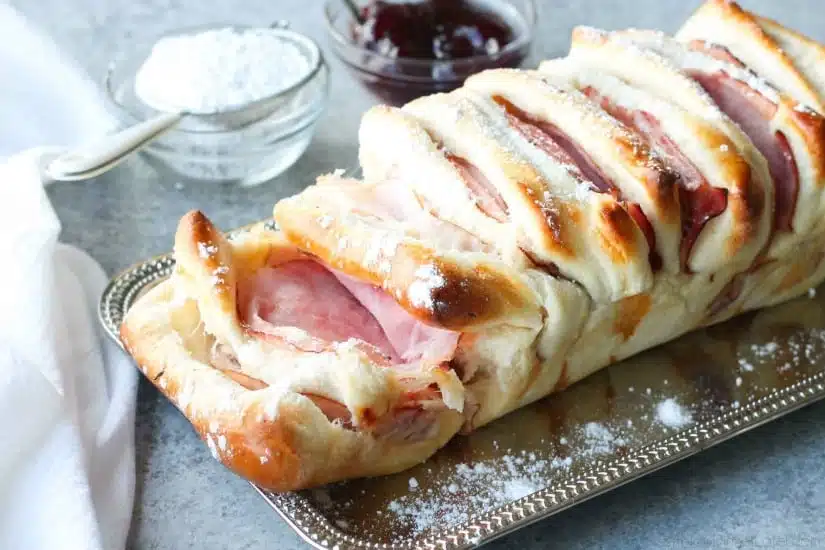 This Monte Cristo Pull Apart Bread is full of savory meats and melty cheese. It's topped with a dusting of powdered sugar and served with raspberry preserves. Works great as a breakfast, lunch, dinner, or appetizer!