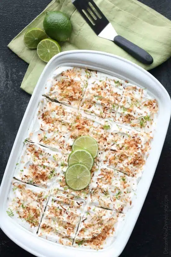 Coconut Lime Poke Cake - a fluffy, white, lime-infused cake that is soaked with coconut cream, and topped with sweetened whipped cream, toasted coconut, and lime zest. It's super moist and full of tropical flavors!