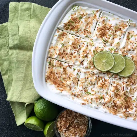 Coconut Lime Poke Cake - a fluffy, white, lime-infused cake that is soaked with coconut cream, and topped with sweetened whipped cream, toasted coconut, and lime zest. It's super moist and full of tropical flavors!