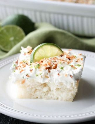 Coconut Lime Poke Cake - a fluffy, white, lime-infused cake that is soaked with coconut cream, and topped with sweetened whipped cream, toasted coconut, and lime zest. It's super moist and full of tropical flavors!