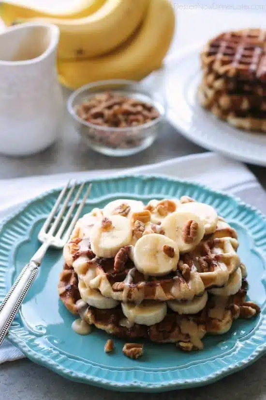 Cinnamon Roll Waffles are topped with freshly sliced bananas, crunchy nuts, and a maple cream cheese drizzle.