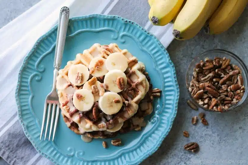 Cinnamon Roll Waffles are topped with freshly sliced bananas, crunchy nuts, and a maple cream cheese drizzle.