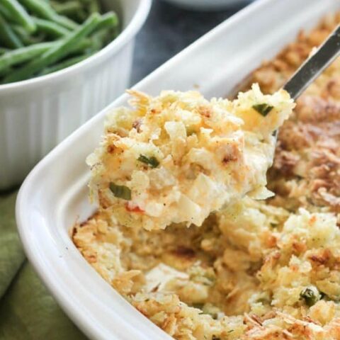 These funeral potatoes are creamy and cheesy, with sour cream, onions, extra spices, and a crunchy potato chip topping. Always a hit, this cheesy potato casserole will get gobbled up quick! Great for potlucks and holidays.