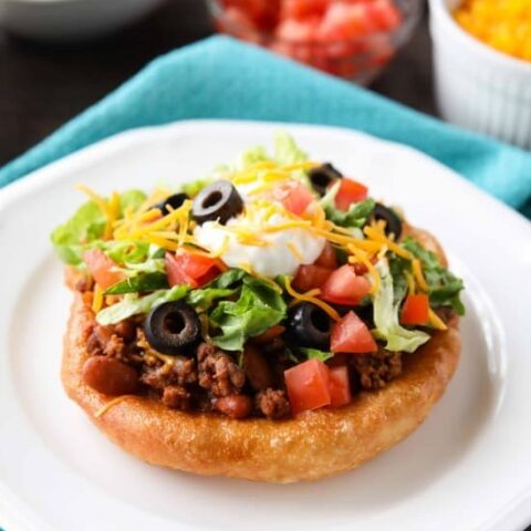 These easy Navajo Tacos (also known as Indian Fry Bread) are quick to whip up for dinner, smothered with a beef and bean taco filling, and finished with all the classic taco toppings. A fair food favorite made easily at home!
