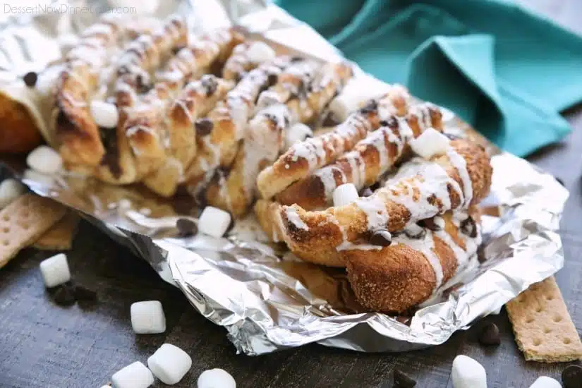 S'mores Pull Apart Bread is loaded with graham cracker crumbs, marshmallows, and chocolate chips, then topped off with a marshmallow glaze for a camping inspired dessert you can enjoy anytime!