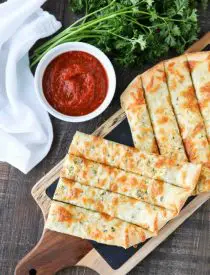 These easy Cheesy Garlic Breadsticks are loaded with garlic, cheese, and herbs for a great tasting breadstick to enjoy for pizza night. Also delicious dipped in marinara sauce!