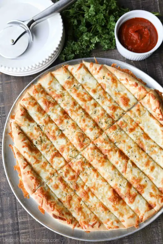 These easy Cheesy Garlic Breadsticks are loaded with garlic, cheese, and herbs for a great tasting breadstick to enjoy for pizza night. Also delicious dipped in marinara sauce!