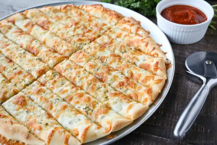 These easy Cheesy Garlic Breadsticks are loaded with garlic, cheese, and herbs for a great tasting breadstick to enjoy for pizza night. Also delicious dipped in marinara sauce!