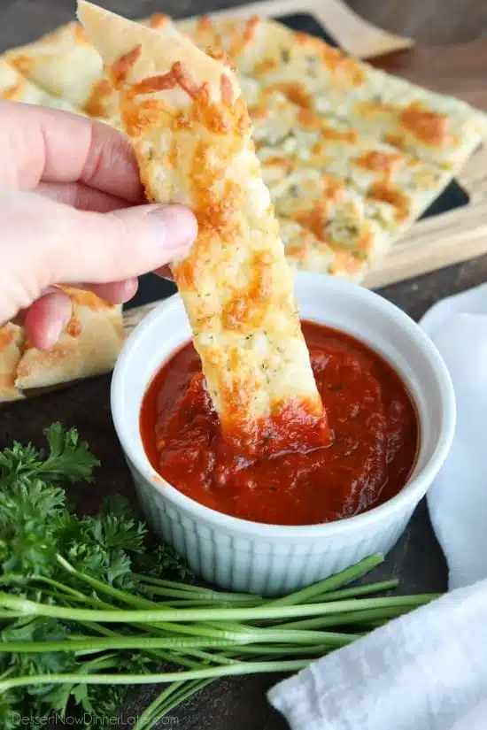 These easy Cheesy Garlic Breadsticks are loaded with garlic, cheese, and herbs for a great tasting breadstick to enjoy for pizza night. Also delicious dipped in marinara sauce!