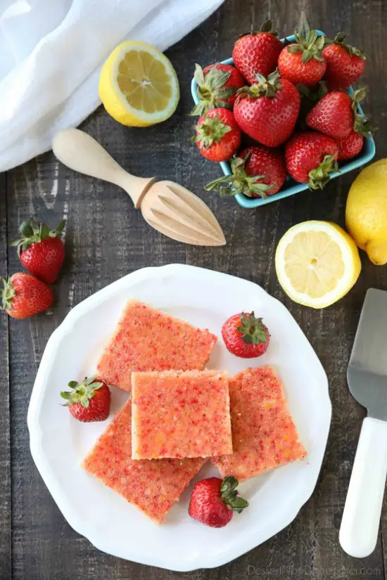 Squares of strawberry and lemon bars on plate with fresh strawberries.