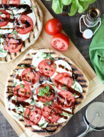 Grilled Caprese Flatbread makes a great summer dinner or appetizer. Freshly grilled bread is topped with mozzarella, tomatoes, basil, and garlic, then drizzled with a simple balsamic glaze. 