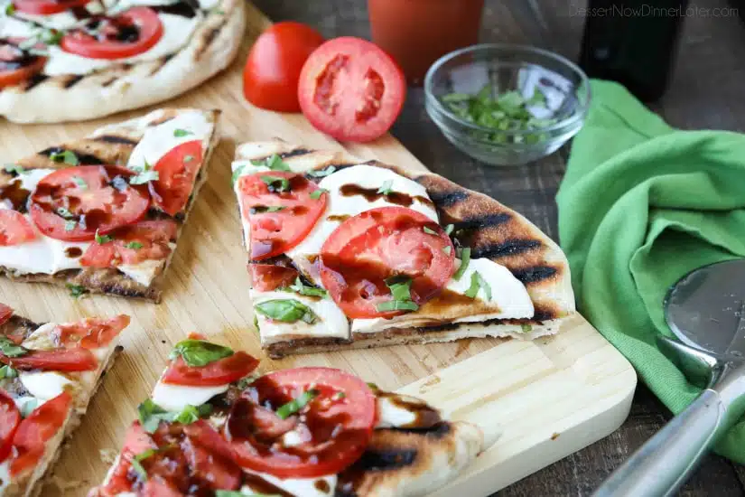 Grilled Caprese Flatbread makes a great summer dinner or appetizer. Freshly grilled bread is topped with mozzarella, tomatoes, basil, and garlic, then drizzled with a simple balsamic glaze. 