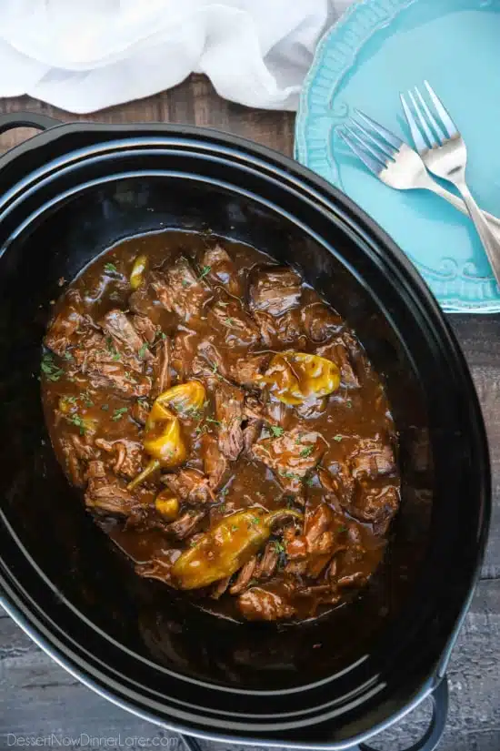 Slow cooker filled with shredded Mississippi Pot Roast in gravy.