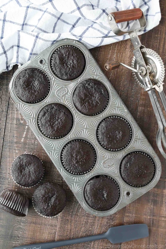Baked chocolate cupcakes in pan and on table.