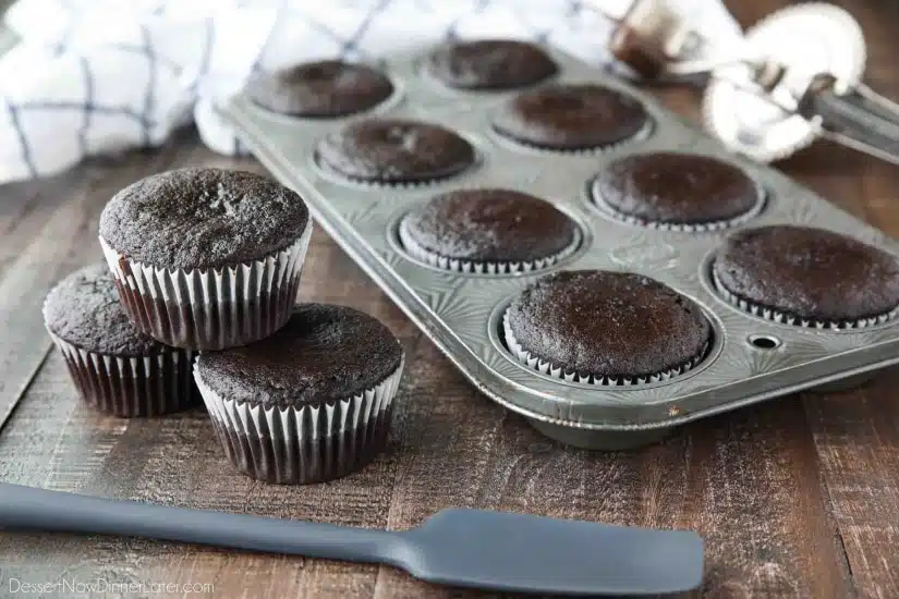 Baked chocolate cupcakes in pan and on table.