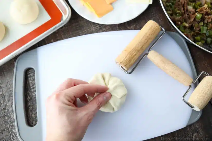 Wrapping dough around filling and pinching shut.