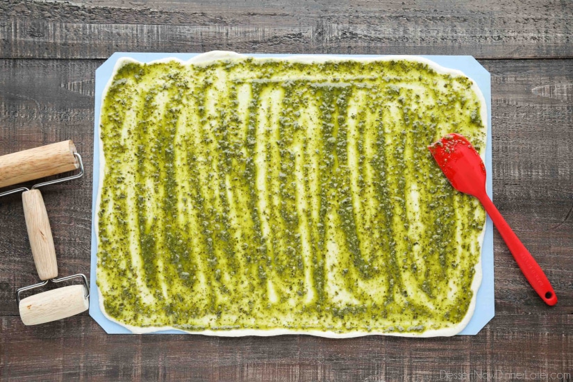 Rhodes bread dough rolled into a rectangle with pesto spread on top.