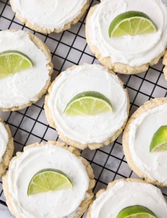 Coconut Lime Sugar Cookies - an easy sugar cookie recipe with a tropical fruit twist. You'll love these moist sugar cookies with a hint of lime, creamy coconut frosting, and a fresh lime wedge to squeeze on top. A Twisted Sugar copycat recipe.