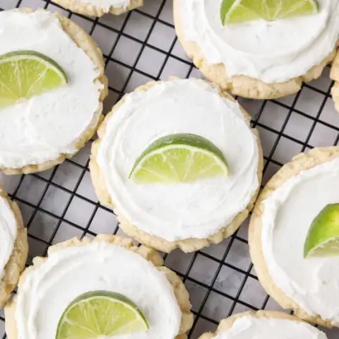 Coconut Lime Sugar Cookies - an easy sugar cookie recipe with a tropical fruit twist. You'll love these moist sugar cookies with a hint of lime, creamy coconut frosting, and a fresh lime wedge to squeeze on top. A Twisted Sugar copycat recipe.